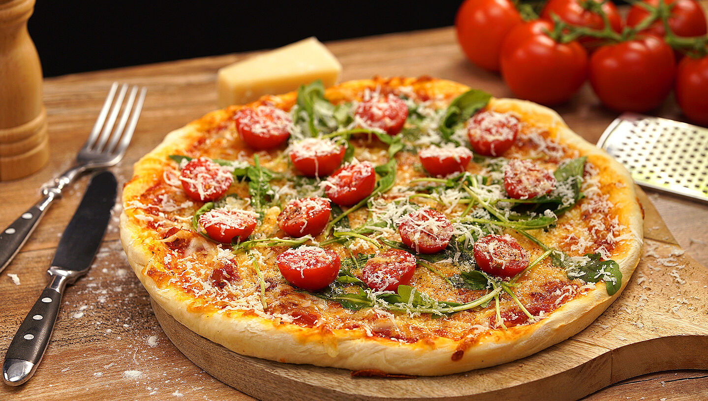 Selbstgemachte Pizza mit Rucola und Tomaten