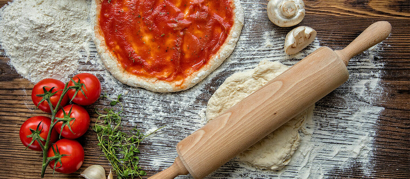 Pizza dough with tomato soup and ingredients.