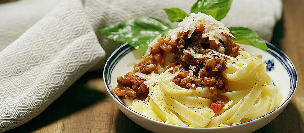 Tagliatelle al ragu bolognese in a white bowl.