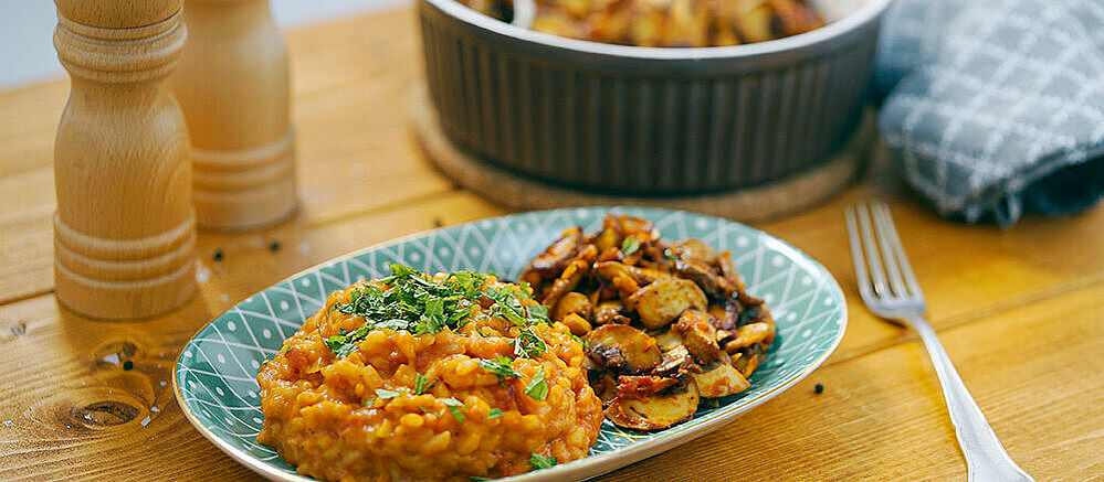 Tomato risotto with fried garlic mushrooms in a turquoise plate.
