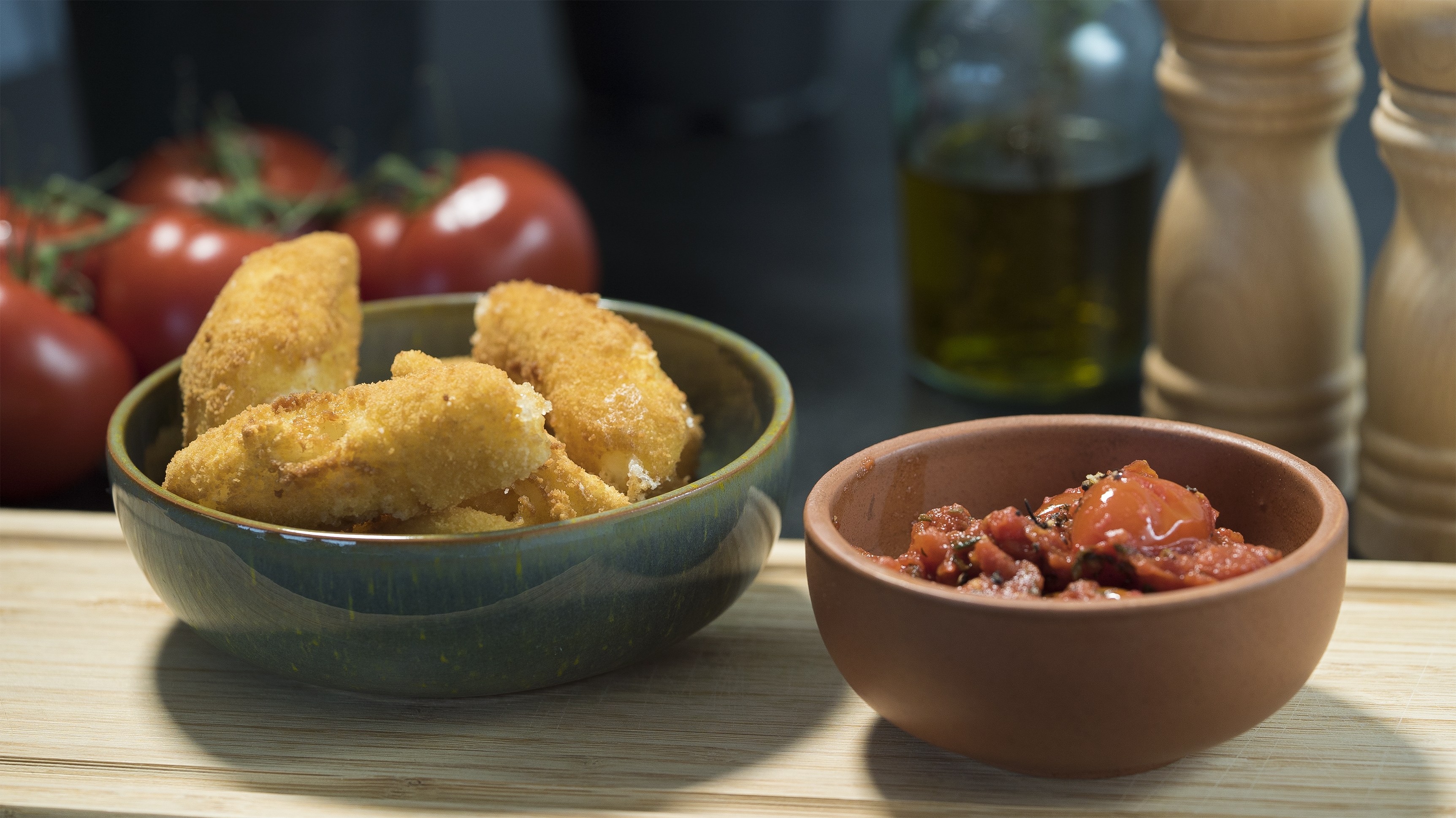 Mozzarella sticks in a green bowl and a smaller bowl with a dip next.