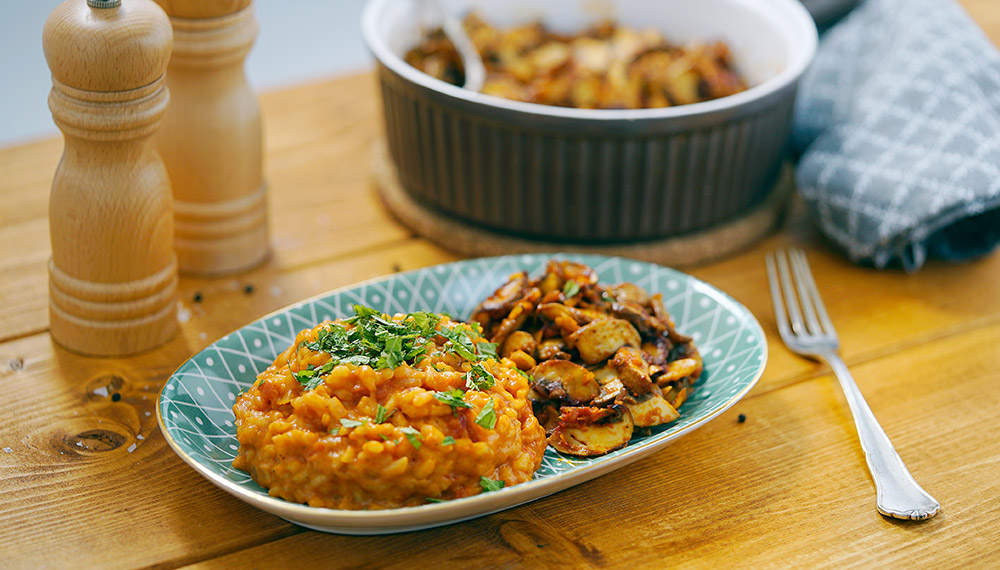 Tomato risotto with fried garlic mushrooms in a turquoise plate.